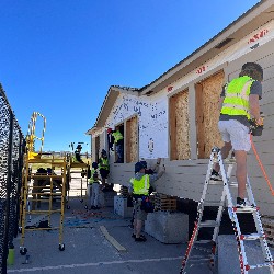 Students work on the exterior of a house.